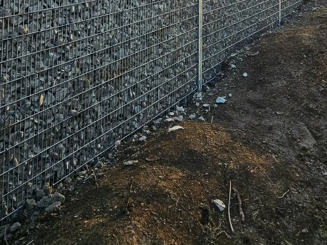 Spodek sypané gabionové stěny se sloupky STONE těsně po montáži, kolem čerstvě upravená zemina
