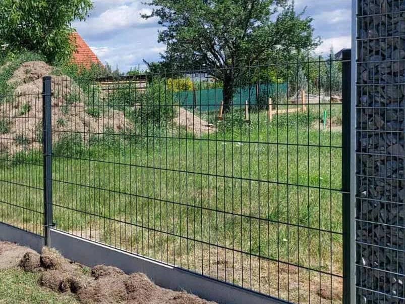 Konec sypané gabionové stěny, na který navazuje plot z 2D panelů
